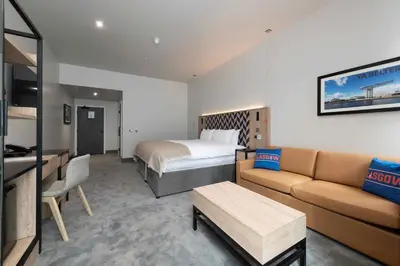 a hotel room with a bed and a couch at Sandman Signature Glasgow Hotel in Glasgow