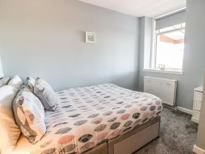 a bedroom with a bed with a comforter and a window at Rothiemay in Girvan