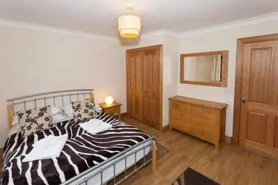 a bedroom with a black and white bed and a dresser at Appletree Cottage at Williamscraig Holiday Cottages in Linlithgow