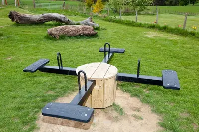 a trampoline park with a wooden table and trampoline at Beech Cottage at Williamscraig Holiday Cottages in Linlithgow