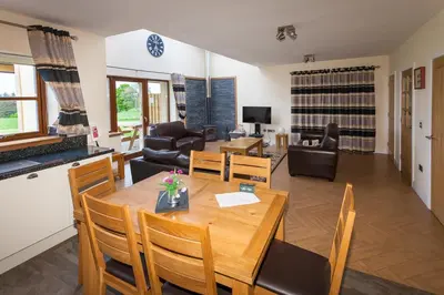 a dining room and living room with a table and chairs at 1 Eden at Williamscraig Holiday Cottages in Linlithgow
