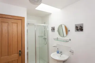 a bathroom with a shower and a sink and a mirror at Honeysuckle Cottage at Williamscraig Holiday Cottages in Linlithgow