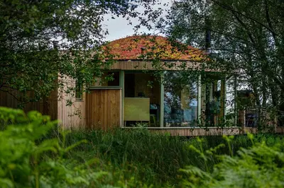 a small house with a large window in a field at Craigmaddie Muir Roundhouse with Hot Tub Romantic, Luxury, Rural Stay for 2 Near Milngavie in Glasgow
