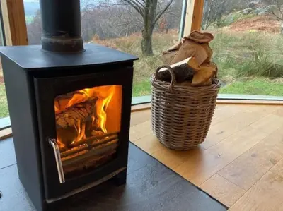 a black stove with a basket next to a window at Craigmaddie Muir Roundhouse with Hot Tub Romantic, Luxury, Rural Stay for 2 Near Milngavie in Glasgow