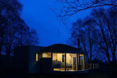 a small house in the middle of the woods at night at Craigmaddie Muir Roundhouse with Hot Tub Romantic, Luxury, Rural Stay for 2 Near Milngavie in Glasgow