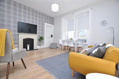 a living room with a yellow couch and a fireplace at The Warren Apartment in Greenock