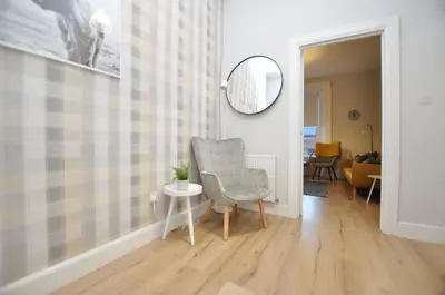 a living room with a chair and a mirror at The Warren Apartment in Greenock