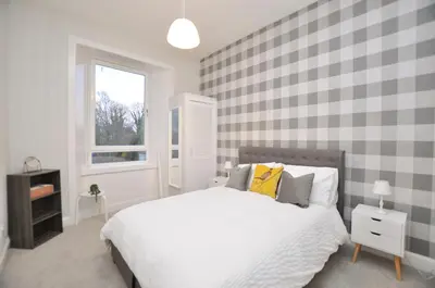 a bedroom with a white bed and a window at The Warren Apartment in Greenock