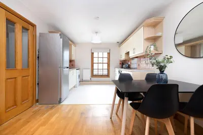a kitchen with a table and chairs and a refrigerator at JOIVY Bright and Cosy Flat near The Scotland Gallery in Edinburgh