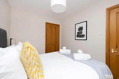a bedroom with a white bed with white sheets at JOIVY Bright and Cosy Flat near The Scotland Gallery in Edinburgh