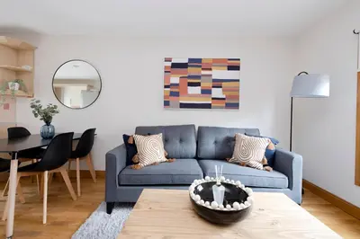 a living room with a blue couch and a table at JOIVY Bright and Cosy Flat near The Scotland Gallery in Edinburgh
