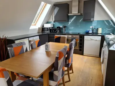 a kitchen with a wooden table and chairs at Lochside Apartment in Stronachlachar
