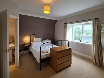 a bedroom with a bed and a dresser and a window at Lochside Apartment in Stronachlachar