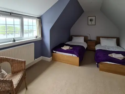 two beds in a room with blue walls and windows at Lochside Apartment in Stronachlachar
