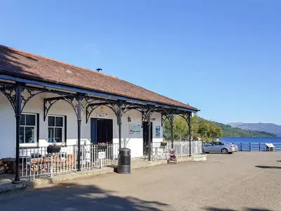 a building with a car parked next to the water at Lochside Apartment in Stronachlachar