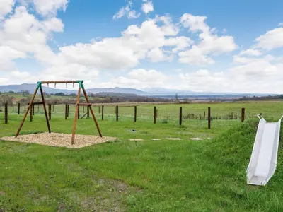 a swing set in a field with a fence at Iora Rua-Uk40006 in Gartmore