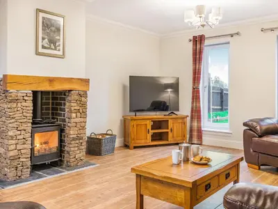 a living room with a fireplace and a tv at Fiadh Ruadh-Uk40008 in Gartmore