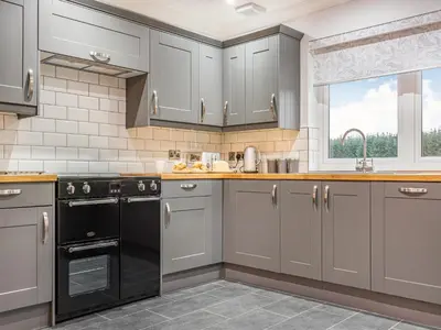 a kitchen with gray cabinets and a black dishwasher at Fiadh Ruadh-Uk40008 in Gartmore