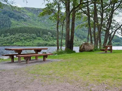 a picnic table in a field next to a lake at Gartclach-Uk40001 in Gartmore