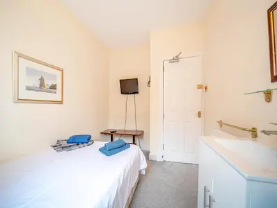 a bedroom with a white bed and a sink at Charles House in Largs
