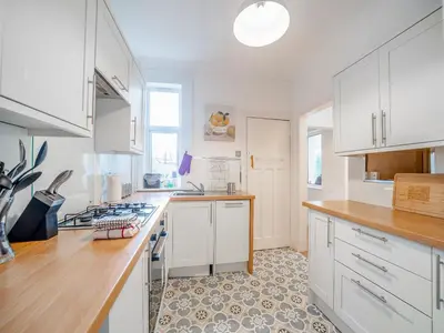 a kitchen with white cabinets and a counter top at Charles House in Largs