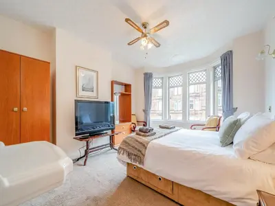 a bedroom with a large bed and a television at Charles House in Largs