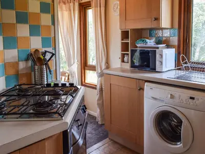 a kitchen with a stove and a washing machine at Teasel Lodge - Uk39647 in Lunga