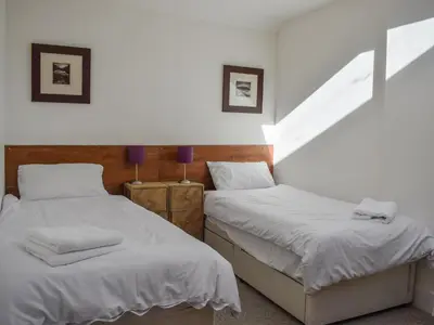 two beds in a room with white sheets at Daisybank Cottage in Crieff