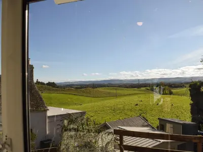 a view of a green field from a window at Daisybank Cottage in Crieff