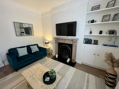 a living room with a blue couch and a fireplace at Traditional Cottage in West Kilbride Village in Seamill