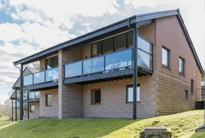 a large brick building with a balcony on the side at Fabulous Lodges at Cameron House, Loch Lomond in Balloch