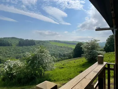 a wooden bench sitting on top of a green field at Ecosse Glamping in Crossford