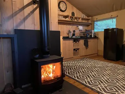a living room with a stove with a fire in it at Ecosse Glamping in Crossford