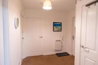 a hallway with a white door and a radiator at Balvenie Apartment in Oban