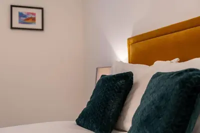 a bed with two green pillows on it at Balvenie Apartment in Oban