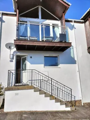 a house with a balcony with a staircase at Seaview cosy 2 bed home in Lamlash - 'Mid Drive' in Lamlash