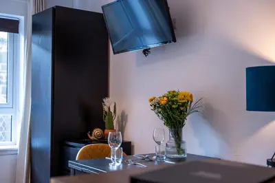 a table with two glasses and a vase of flowers at Springbank Apartment in Oban