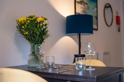 a table with glasses and a vase of flowers on it at Springbank Apartment in Oban