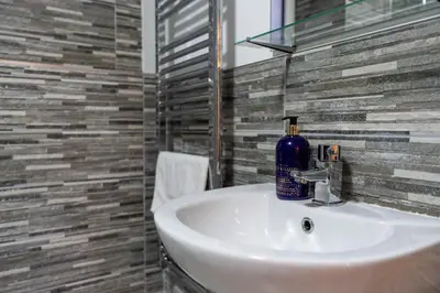 a bathroom with a sink with a blue bottle on it at Lagavulin Apartment in Oban