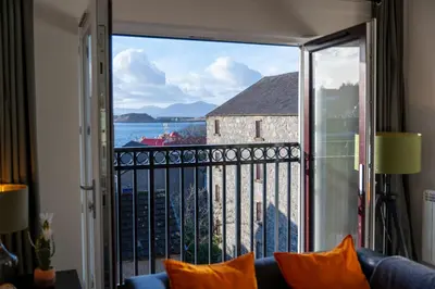 a room with a view of the ocean from a balcony at Ledaig Apartment in Oban