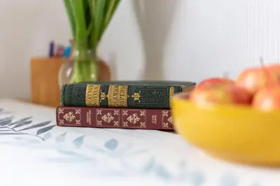 two books sitting on a table with a bowl of apples at Bright & Spacious Double Room with Garden View- Close to Airport & City Centre in Edinburgh