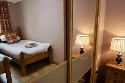 a mirror in a small room with a bed and a lamp at The Old Schoolhouse Lochearnhead in Lochearnhead