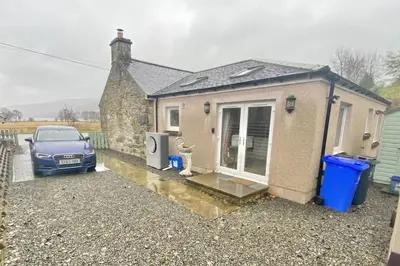 a small house with a car parked in front of it at The Old Schoolhouse Lochearnhead in Lochearnhead
