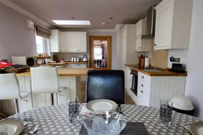 a kitchen with a table and chairs and a kitchen with white cabinets at The Old Schoolhouse Lochearnhead in Lochearnhead