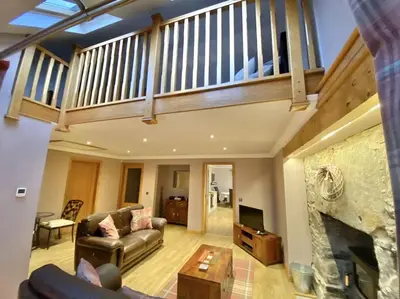 a living room with a couch and a fireplace at The Old Schoolhouse Lochearnhead in Lochearnhead