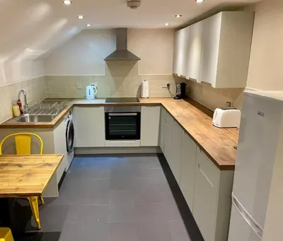 a kitchen with white appliances and a wooden counter top at Vennel Street Apartments in Stewarton