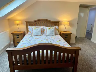 a bedroom with a wooden bed with two night stands at Vennel Street Apartments in Stewarton