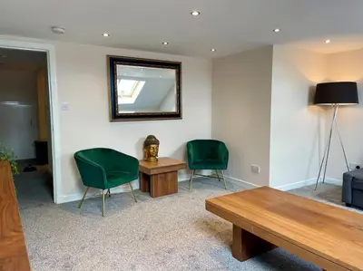 a room with two chairs and a table and a mirror at Vennel Street Apartments in Stewarton