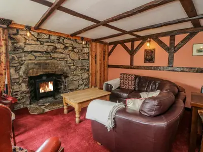 a living room with a couch and a stone fireplace at The House at Bridge of Lochay in Killin