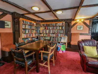 a library with a table and chairs and bookshelves at The House at Bridge of Lochay in Killin